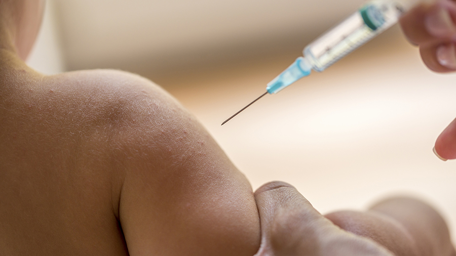 Doctor injecting a young child with a vaccination or antibiotic in a small disposable hypodermic syringe, close up of the kids arm and needle.